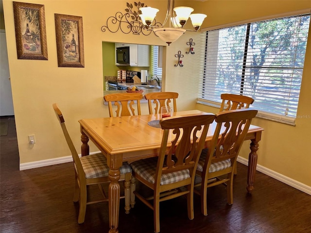 dining area with dark wood-type flooring, sink, and a chandelier