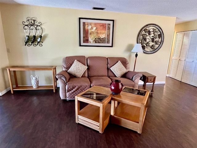 living room with a textured ceiling and dark hardwood / wood-style flooring