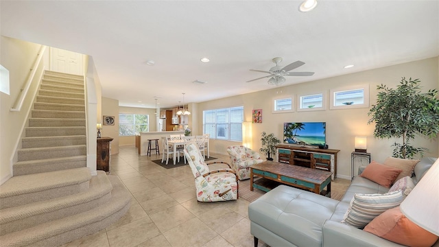 tiled living room featuring ceiling fan with notable chandelier