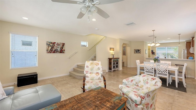 living room with ceiling fan with notable chandelier and light tile patterned floors