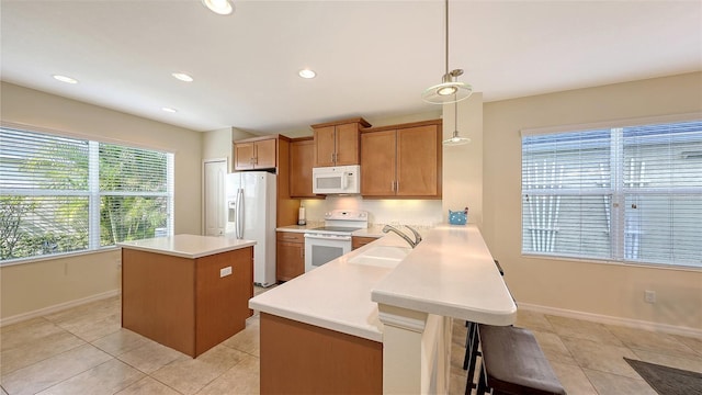 kitchen with sink, white appliances, light tile patterned floors, kitchen peninsula, and hanging light fixtures