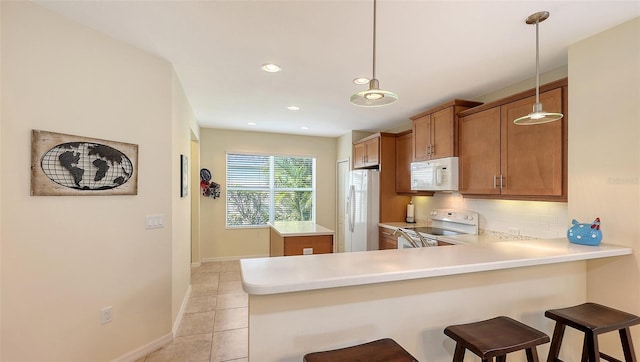 kitchen featuring white appliances, pendant lighting, kitchen peninsula, decorative backsplash, and a breakfast bar