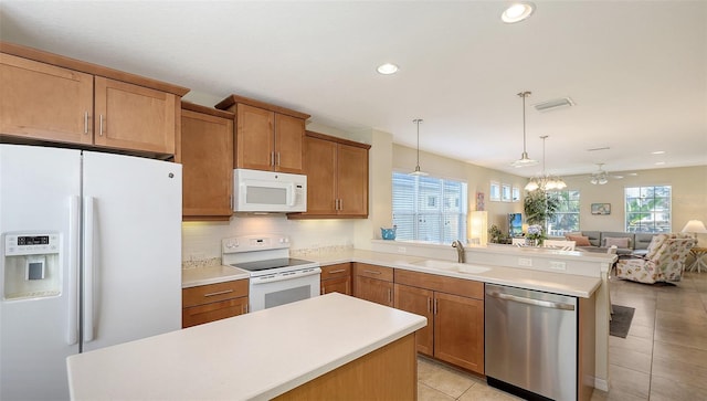 kitchen with white appliances, light tile patterned floors, pendant lighting, sink, and ceiling fan with notable chandelier