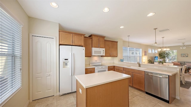 kitchen with white appliances, a center island, decorative light fixtures, light tile patterned floors, and sink