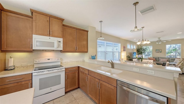 kitchen with white appliances, hanging light fixtures, ceiling fan with notable chandelier, light tile patterned flooring, and sink