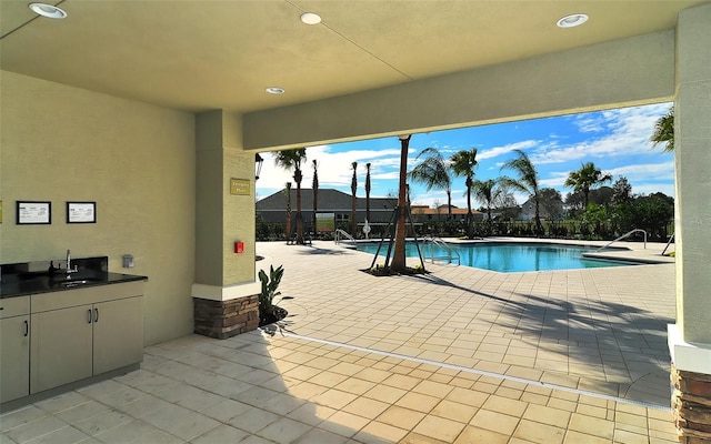 view of pool featuring an outdoor kitchen, a patio, and sink