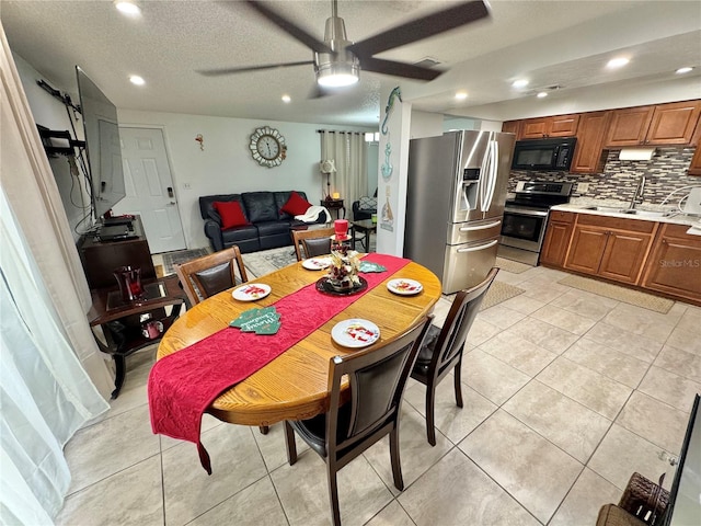 tiled dining area featuring ceiling fan, sink, and a textured ceiling