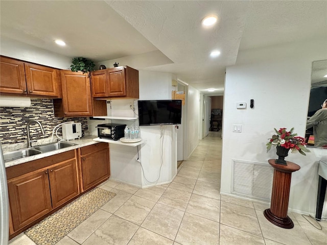 kitchen featuring decorative backsplash, sink, light tile patterned floors, and a textured ceiling