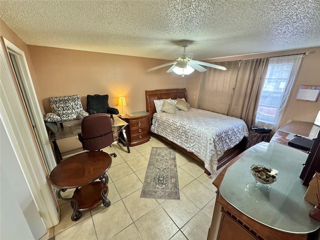 bedroom featuring ceiling fan, light tile patterned floors, and a textured ceiling