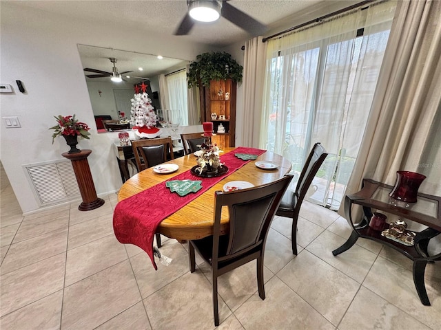 tiled dining space with ceiling fan and a textured ceiling