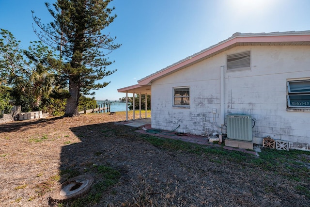 view of side of home with a water view and central AC unit