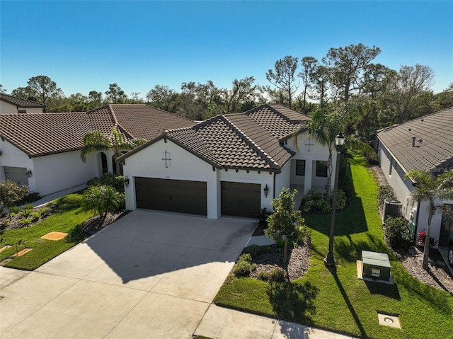 mediterranean / spanish house with central AC unit, a garage, and a front yard