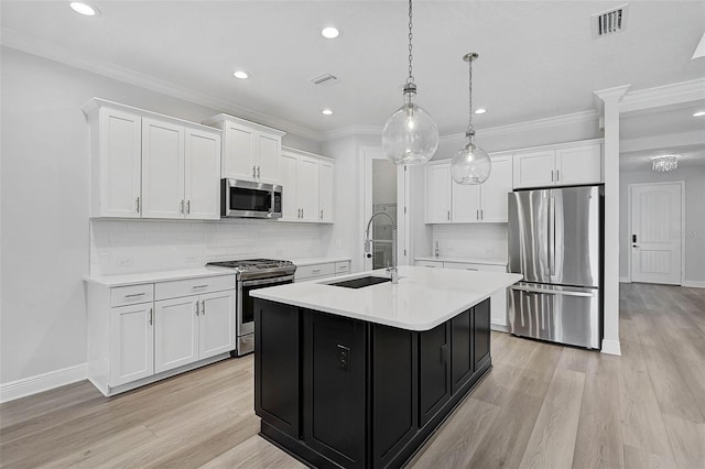 kitchen featuring white cabinets, a center island with sink, sink, decorative light fixtures, and stainless steel appliances