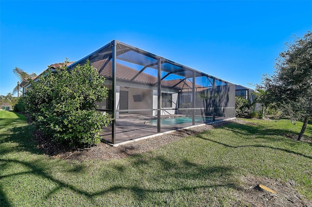 rear view of property with a lawn, glass enclosure, and a patio area