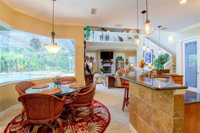 dining space with a fireplace, crown molding, sink, and ceiling fan