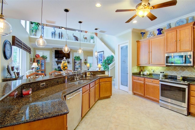 kitchen with crown molding, sink, stainless steel appliances, and hanging light fixtures