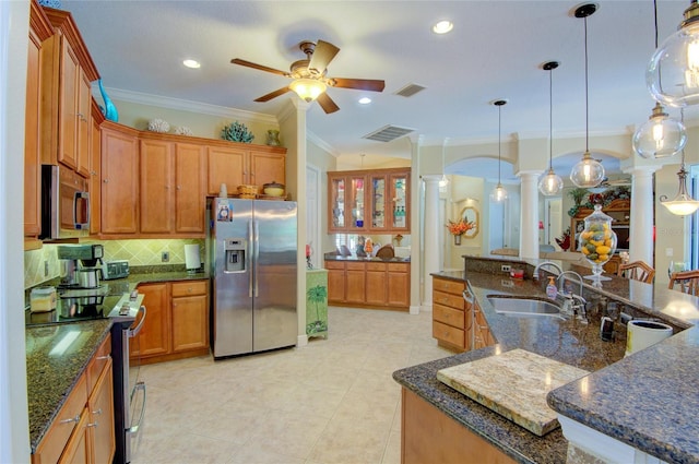 kitchen with pendant lighting, dark stone counters, sink, ornate columns, and stainless steel appliances