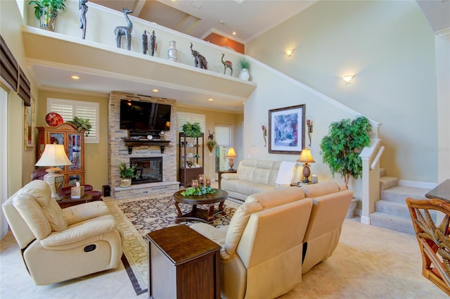 living room featuring light tile patterned floors, a towering ceiling, a stone fireplace, and ornamental molding