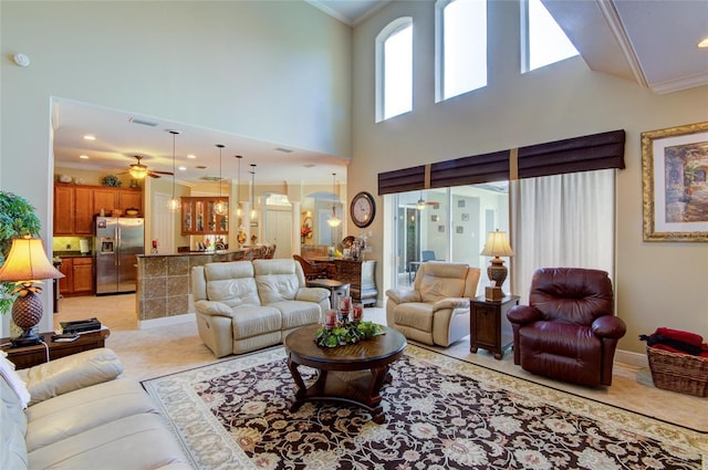 living room with ceiling fan, crown molding, and a high ceiling