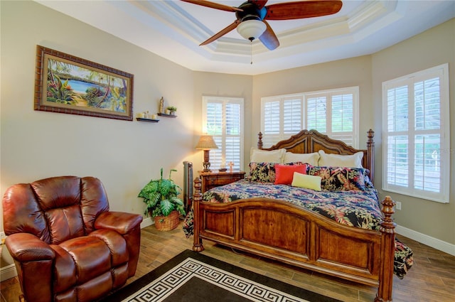 bedroom with a raised ceiling, ceiling fan, crown molding, and wood-type flooring