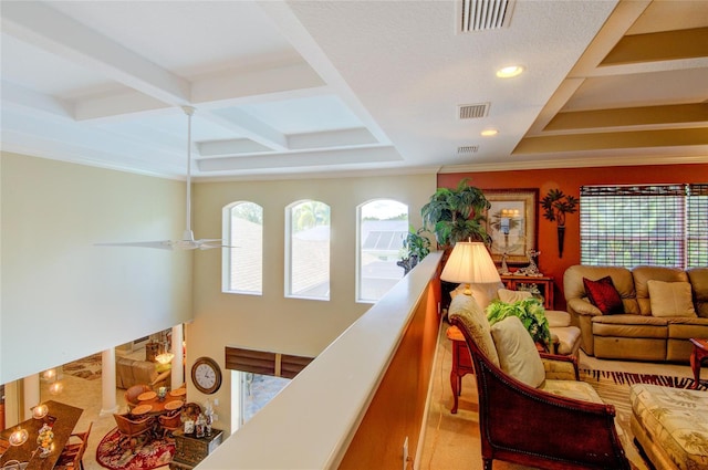 living room with ceiling fan, beamed ceiling, coffered ceiling, and ornamental molding