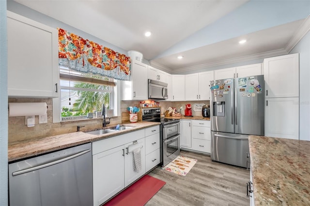 kitchen featuring appliances with stainless steel finishes, white cabinetry, lofted ceiling, and sink