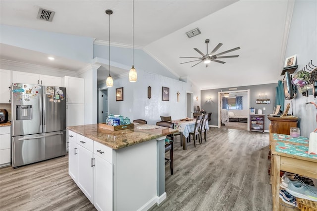 kitchen featuring stainless steel fridge with ice dispenser, white cabinets, light stone countertops, and vaulted ceiling