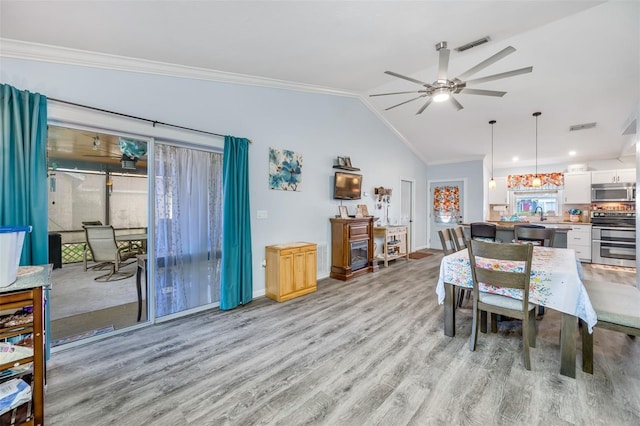 dining area featuring light hardwood / wood-style floors, crown molding, ceiling fan, and lofted ceiling