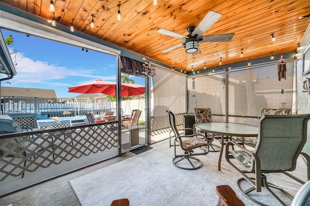 sunroom / solarium with ceiling fan, plenty of natural light, and wood ceiling