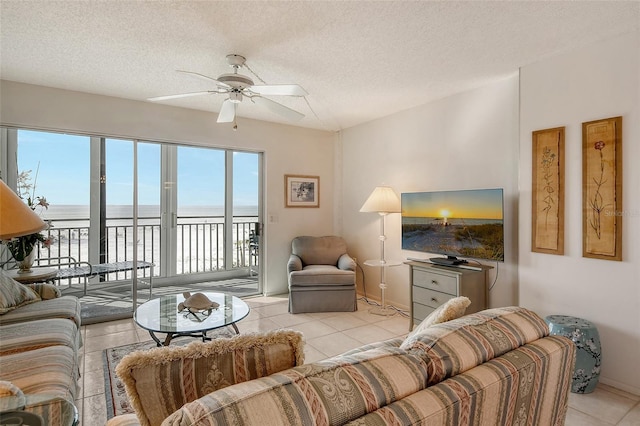 living room with ceiling fan, light tile patterned floors, and a textured ceiling