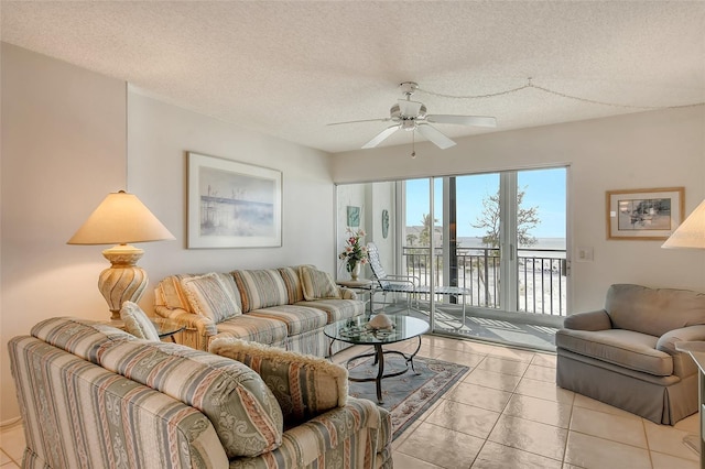 tiled living room with a textured ceiling, a water view, and ceiling fan