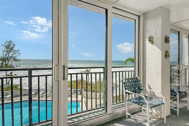 balcony with a water view and a view of the beach