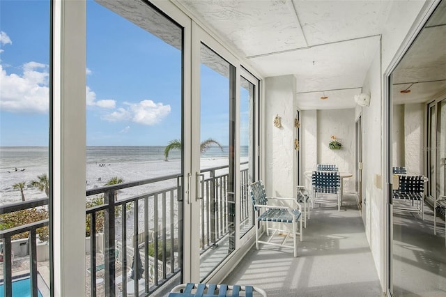 sunroom / solarium featuring a water view and a view of the beach