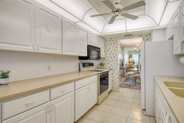 kitchen with range with electric cooktop, ceiling fan with notable chandelier, light tile patterned floors, white refrigerator, and white cabinets