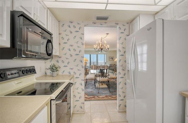 kitchen with white refrigerator with ice dispenser, pendant lighting, white cabinetry, and range with electric stovetop