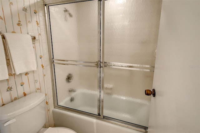 bathroom with toilet and bath / shower combo with glass door