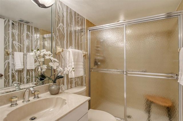 bathroom with vanity, toilet, and a shower with shower door