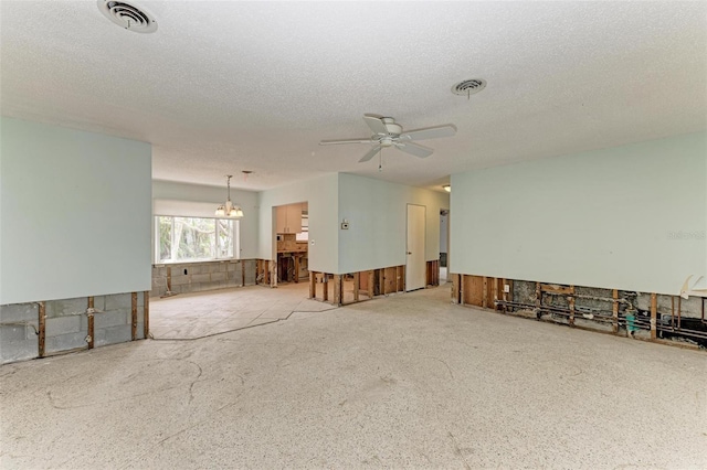 spare room featuring ceiling fan with notable chandelier and a textured ceiling