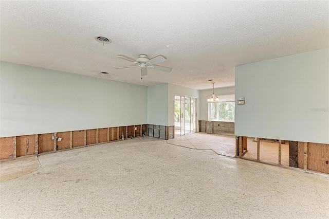 spare room with a textured ceiling and ceiling fan with notable chandelier