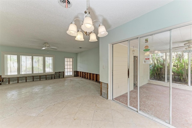 empty room featuring a textured ceiling, tile patterned flooring, and ceiling fan with notable chandelier