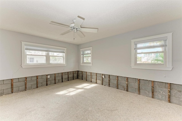 empty room with ceiling fan and a textured ceiling