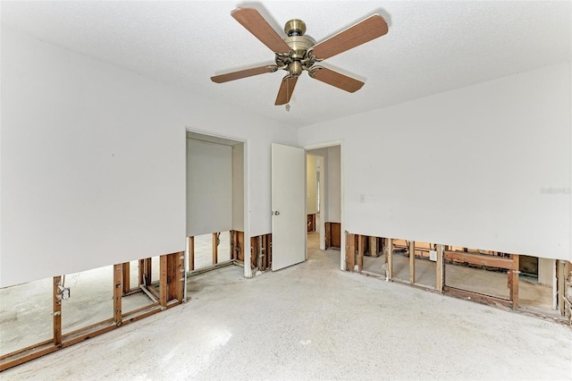 empty room with ceiling fan and a textured ceiling