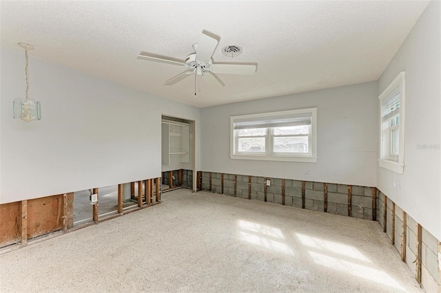 unfurnished room with ceiling fan and a textured ceiling