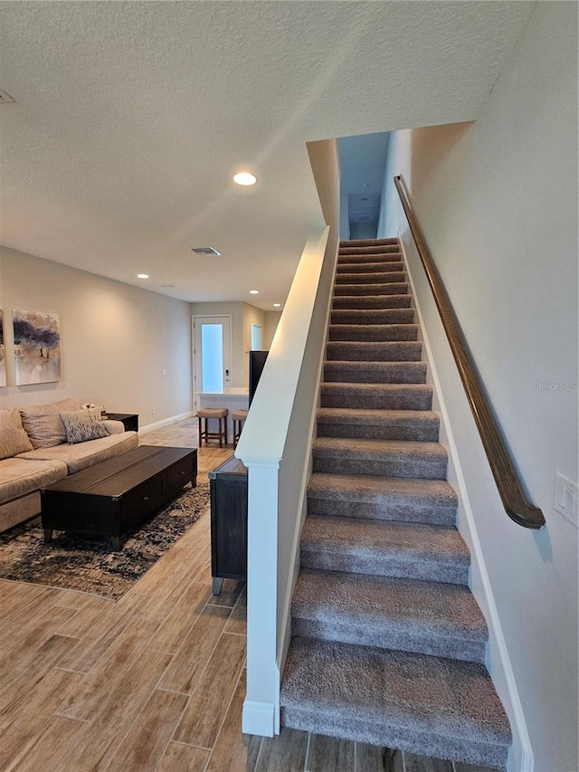 staircase featuring a textured ceiling