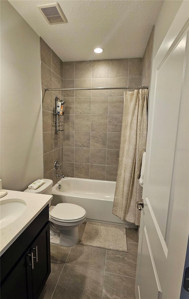 full bathroom with vanity, shower / bath combination with curtain, toilet, and a textured ceiling