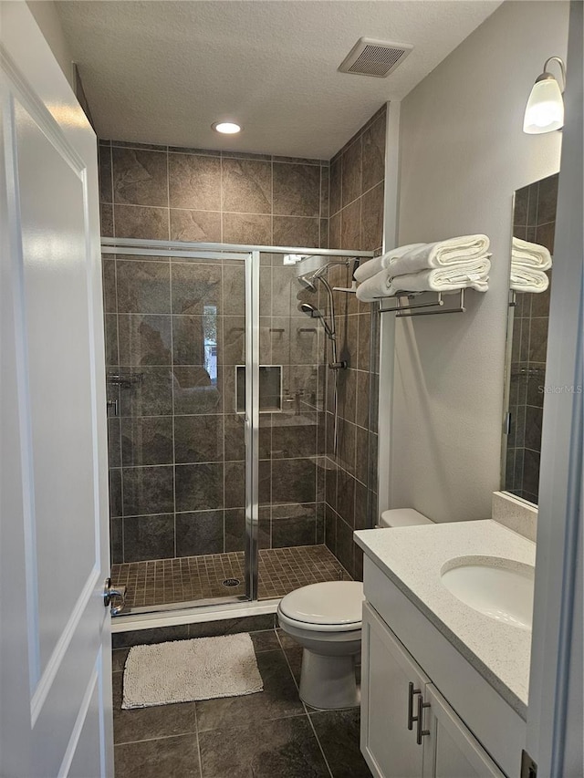 bathroom with tile patterned flooring, vanity, toilet, and an enclosed shower