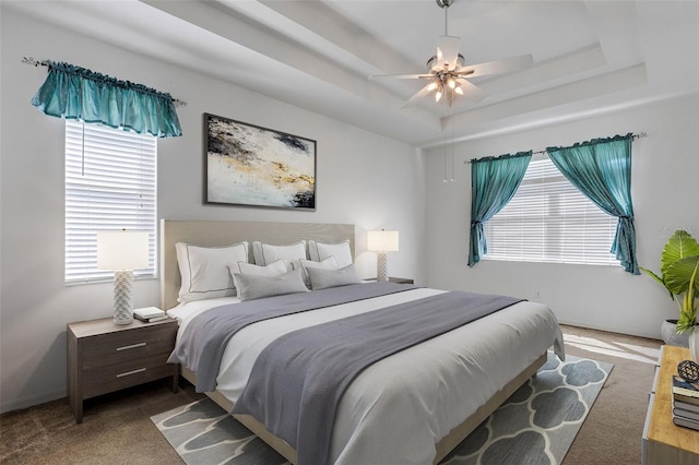 carpeted bedroom featuring a tray ceiling and ceiling fan