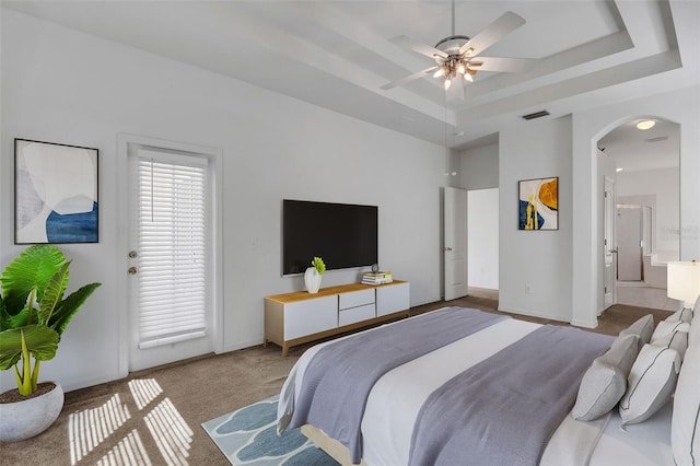 carpeted bedroom featuring connected bathroom, a raised ceiling, and ceiling fan