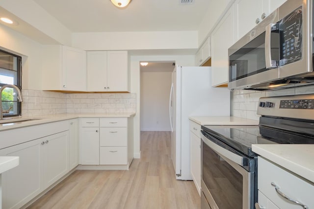 kitchen featuring white cabinets, sink, light wood-type flooring, tasteful backsplash, and stainless steel appliances