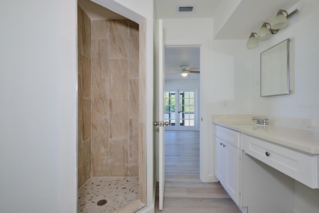 bathroom featuring french doors, a tile shower, vanity, ceiling fan, and hardwood / wood-style floors